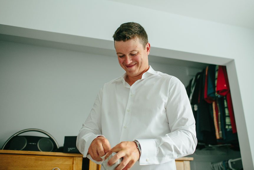 groom opens a gift from his bride as he gets ready for his intimate wedding in Cambridge