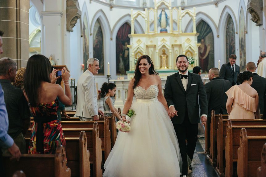 The newly wed bride and groom walks down the aisle as captured by Toronto wedding photojournalist