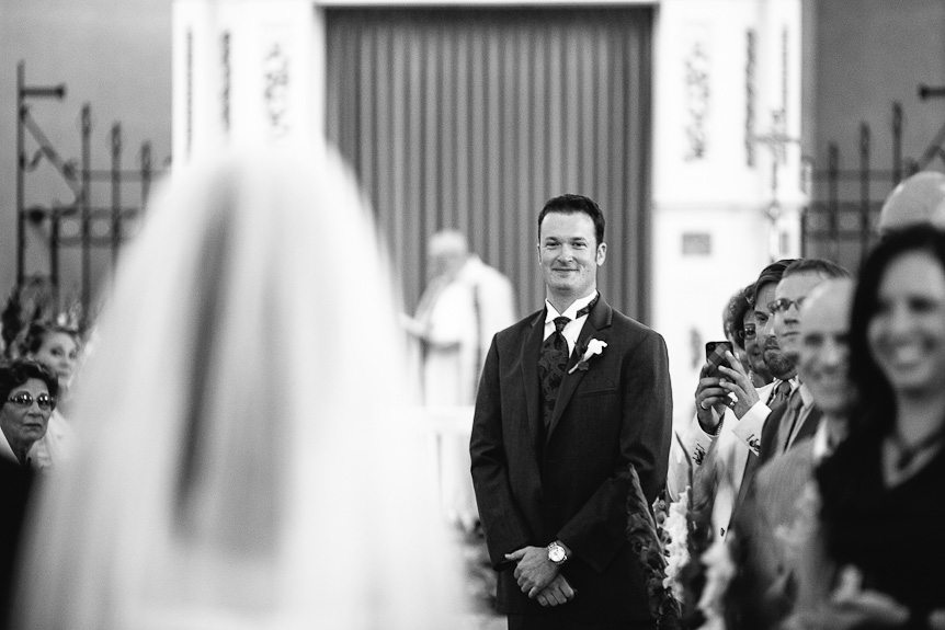 the happy groom sees his bride walking down the aisle captured by  wedding photojournalist