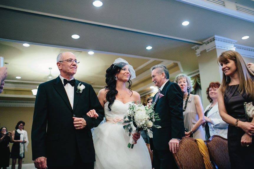beautiful bride walks down the aisle wearing a Vera Wang gown at a Queen's Landing Hotel wedding as captured by Toronto fine art wedding photojournalist