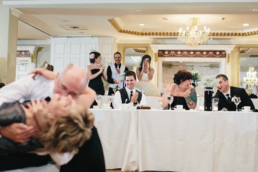 the wedding party reacts to the parents having a ball at their Queen's Landing Hotel wedding reception by fine art wedding photojournalist