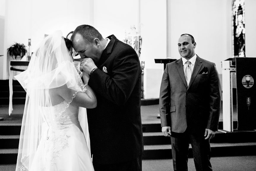 A Cambridge bride and her godfather who walked her down the aisle shares an emotional moment at a Cambridge wedding ceremony as photographed by Cambridge Wedding Photography studio.