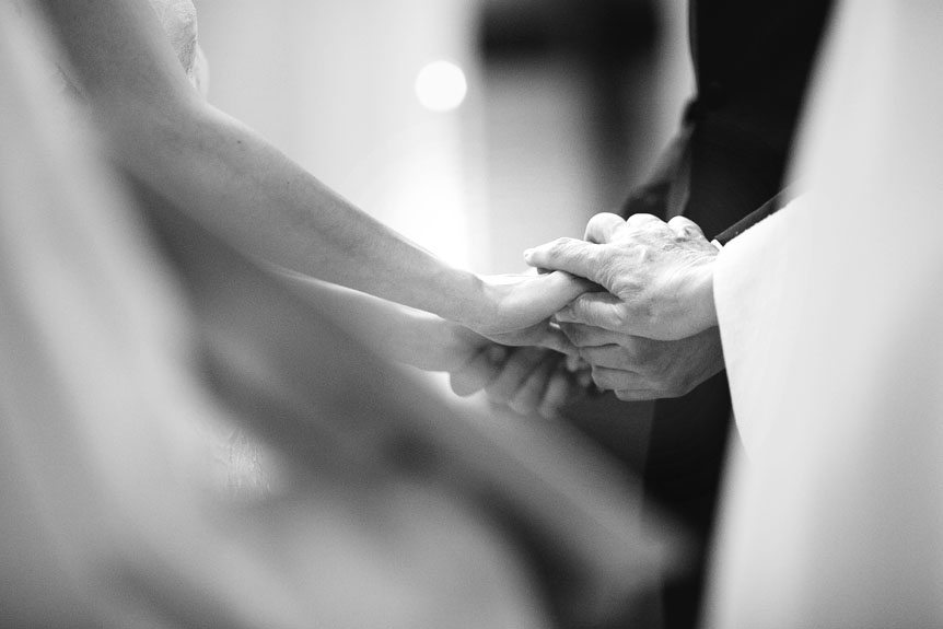 The bride and groom joins hands at their wedding ceremony at the Church of Our Lady Immaculate as photographed by Cambridge Documentary Wedding Photographer.