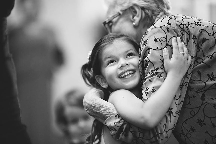 A pretty little girl gets to hug grandma at a wedding reception at the Burlington Convention Center as photographed by Toronto documentary wedding photographer.