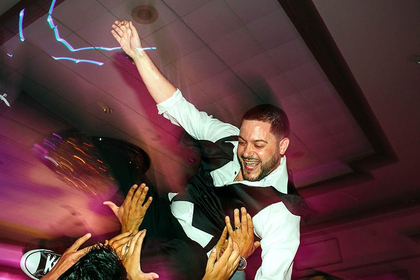 A candid shot of the groom in the air at a wedding reception in Burlington Convention Center as photographed by Toronto documentary wedding photographer.
