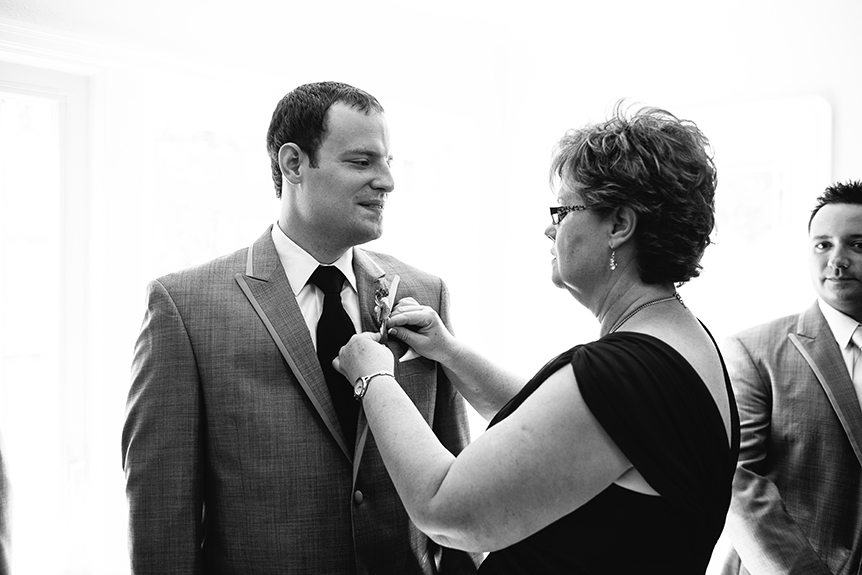The mother of the groom pins his bouttonniere.