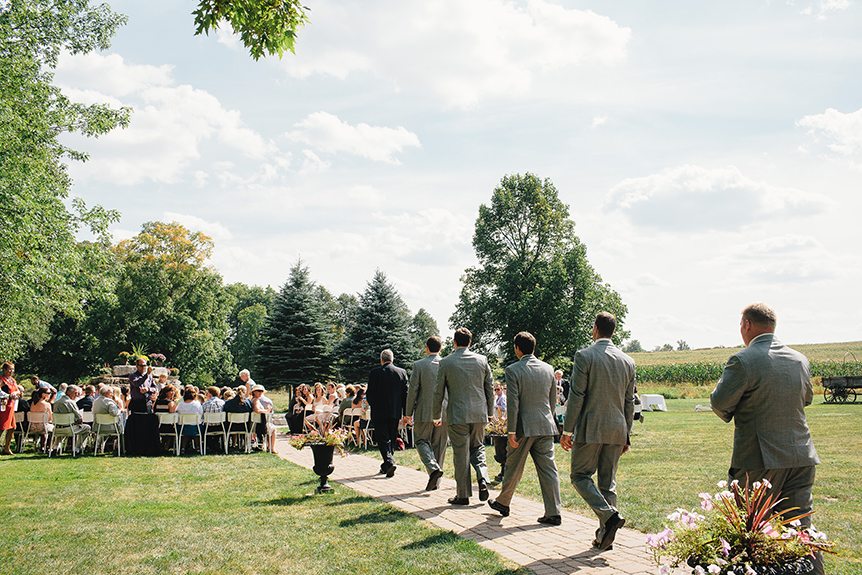 The groom and his groomsmen walk down the aisle at the beginning of their Three Bridges Banquet Hall wedding.