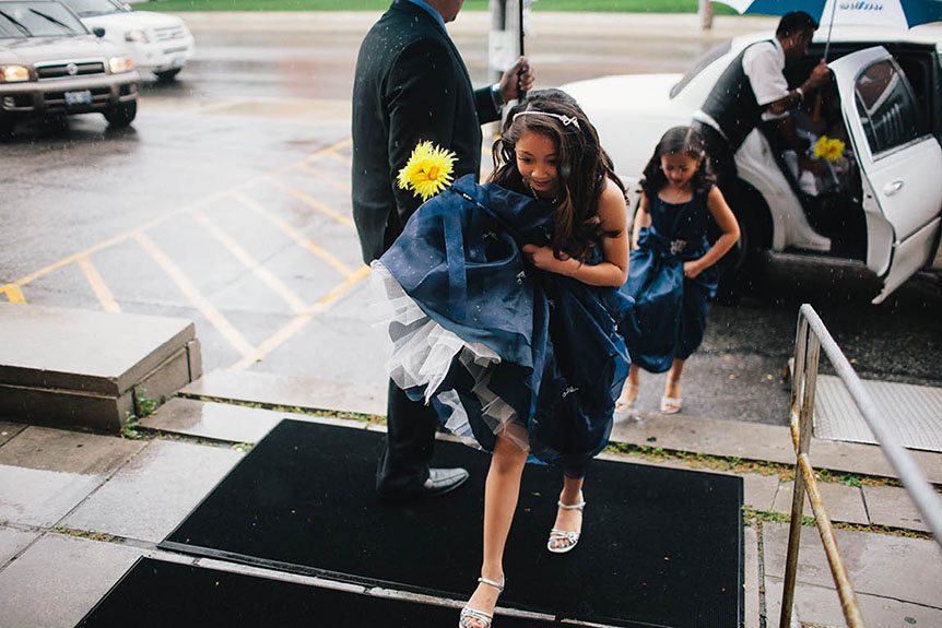 Flower girls run to the church for cover from the rain.