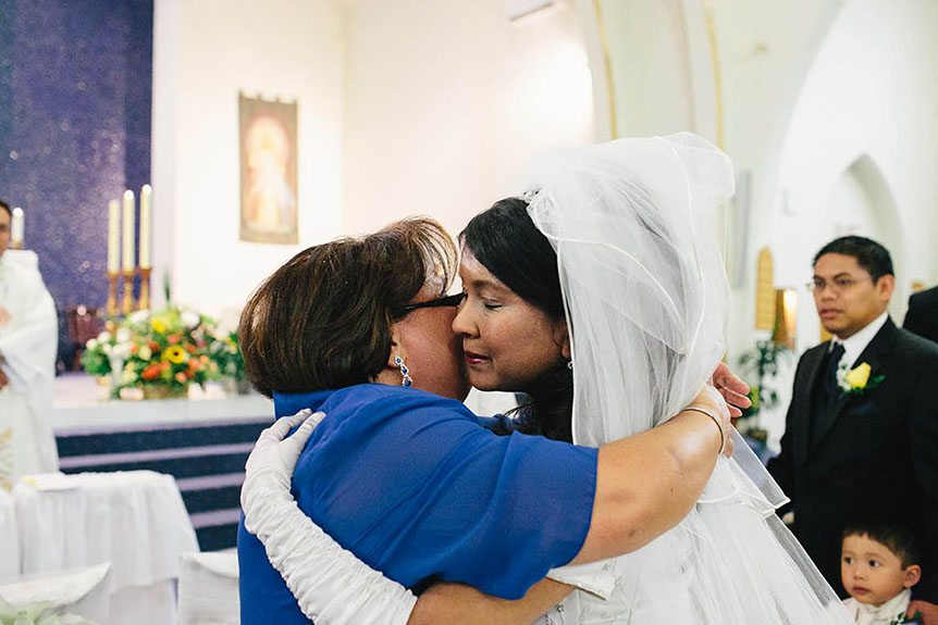 A Filipino bride hugs her mom as she is given away at her wedding.