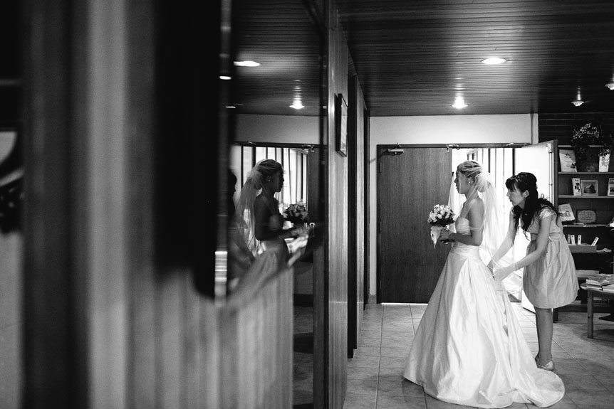 The bride gets ready in front of a mirror before their wedding ceremony.