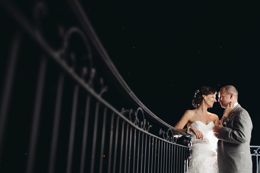 The best Toronto wedding photographer photographs a bride and groom at night at the Cambridge Mill balcony.