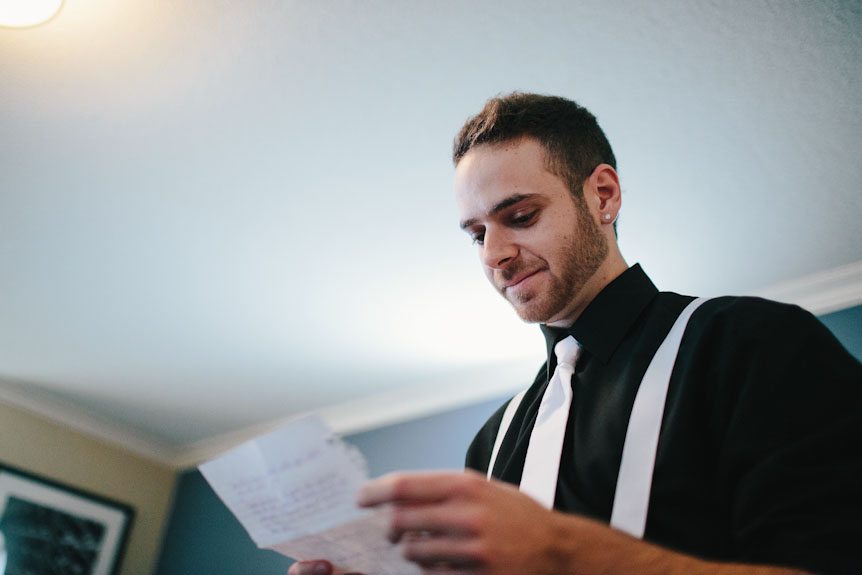 A candid image of the groom as he reads a letter from his bride.