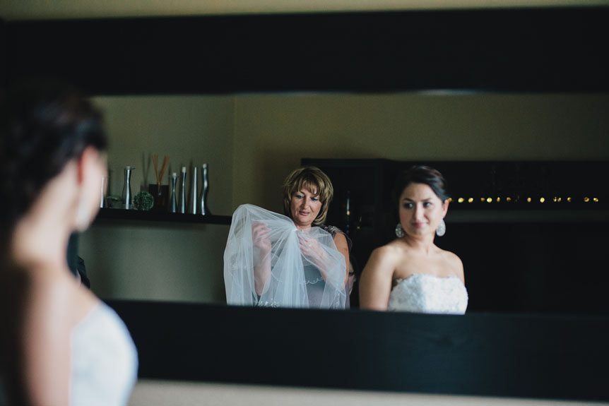 A bride's mother helps her daughter put her veil on.