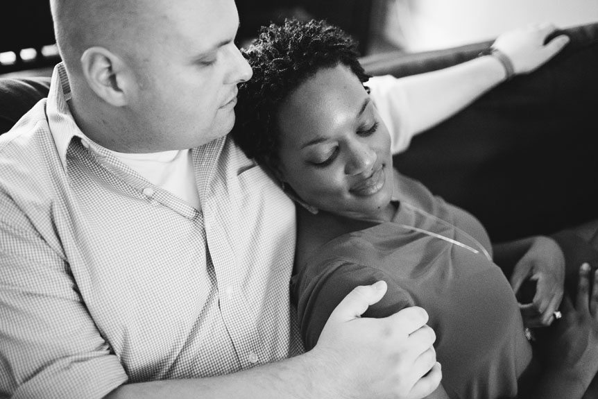 A black and white engagement portrait of a couple at their apartment.