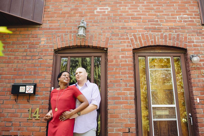 An engaged couple in front of their Toronto townhome.