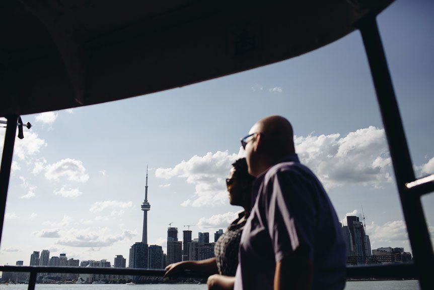 Couple on their way to do their Toronto Islands engagement session with the CN tower in the background.