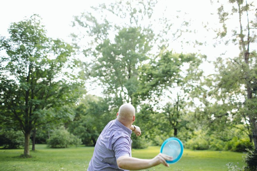 Man plays golf frisbee at a documentary engagement session at the Toronto Islands.