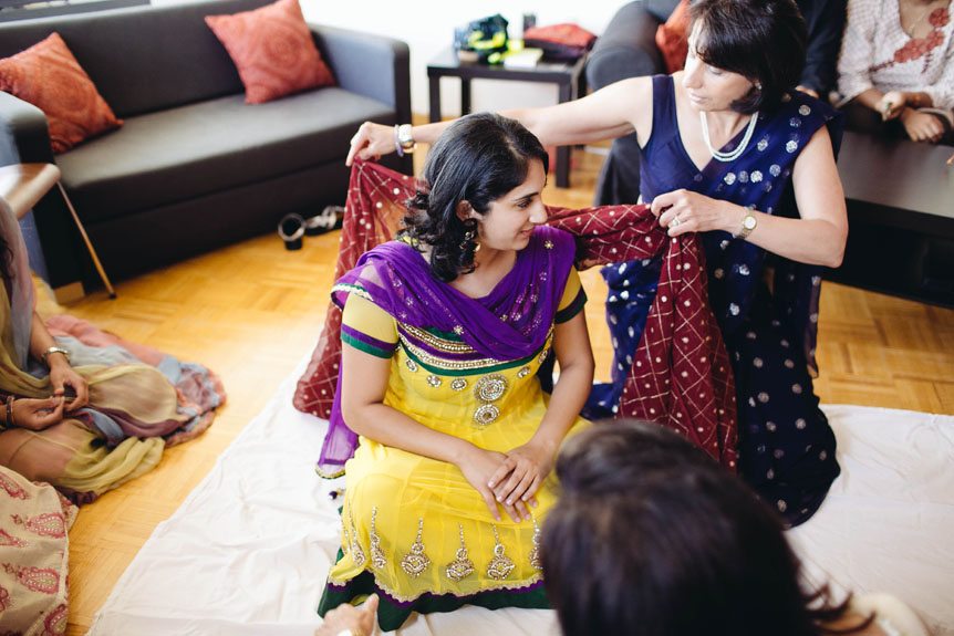 The bride's aunt puts the veil on an Indian bride on her mhendi ceremony.