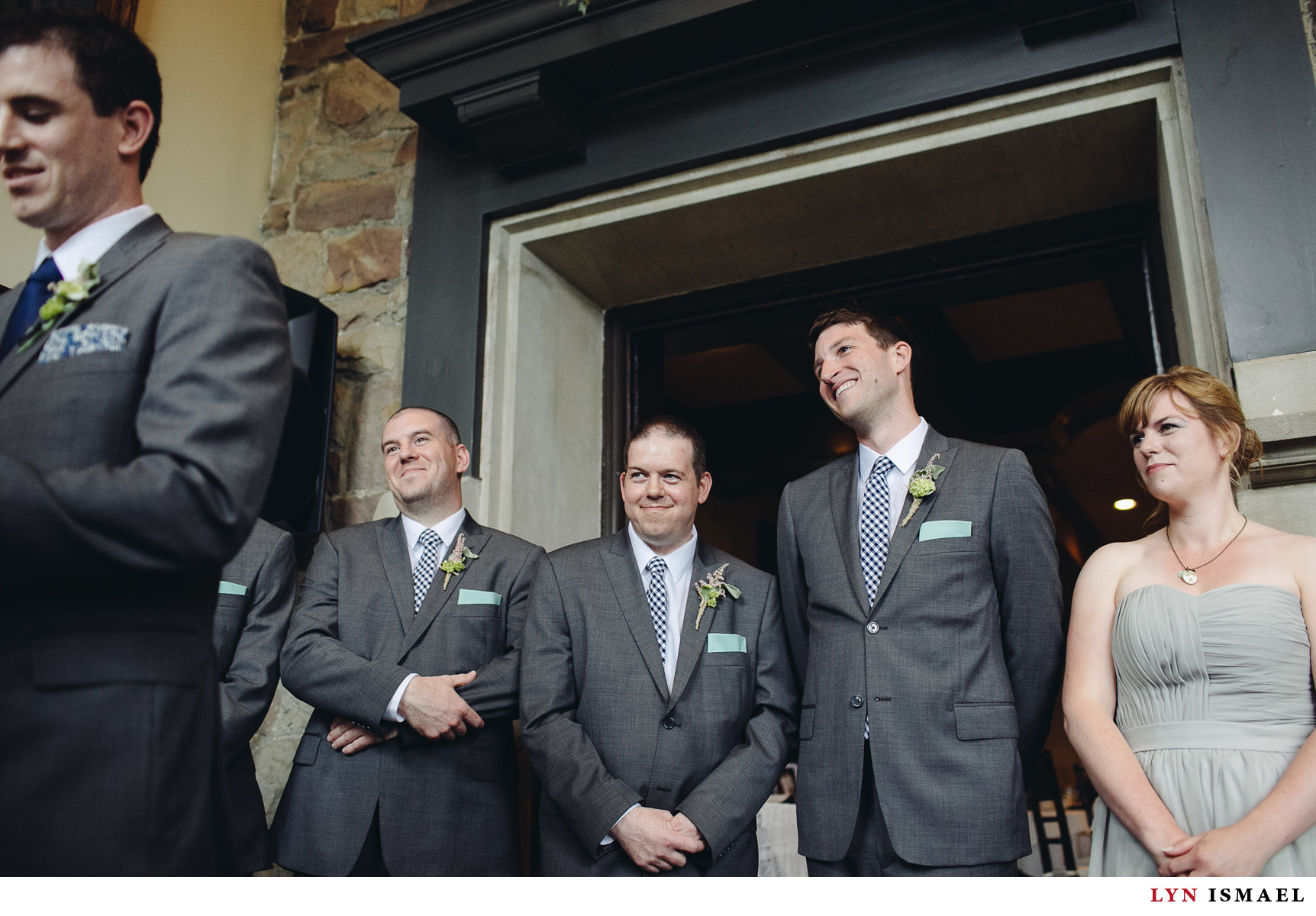 The groom's groomsmen smile happily as they watched the groom say his vows.