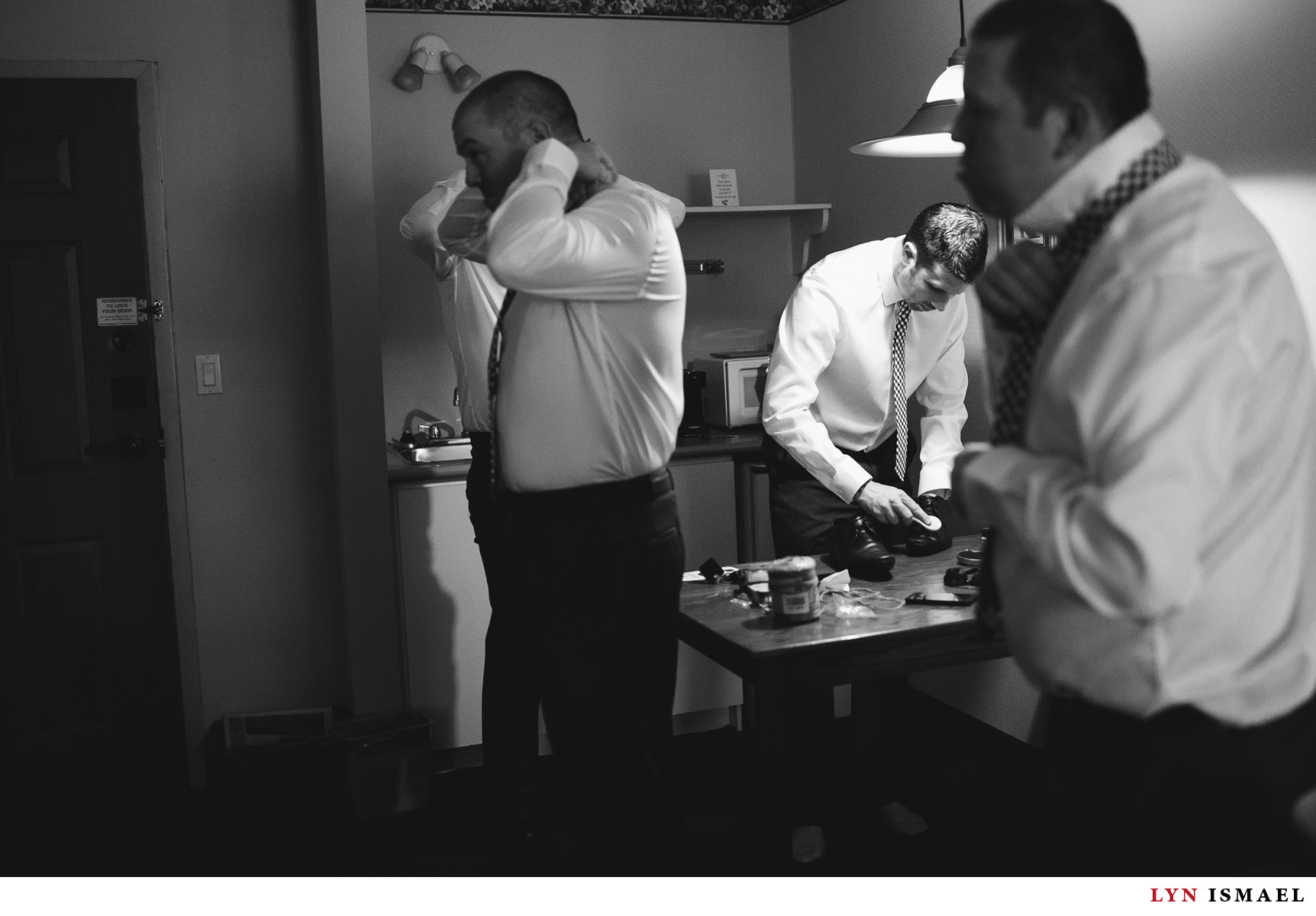 The groomsmen get ready in a hotel room with the groom