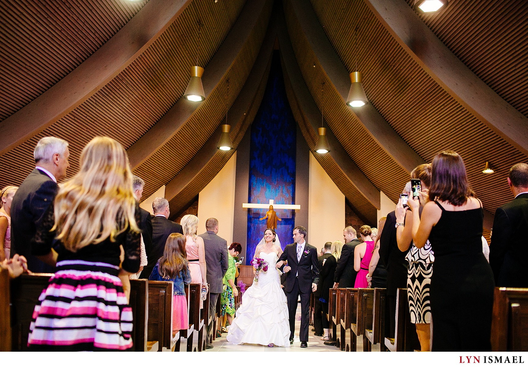 The bride and groom walks down the aisle of the St Mike's Catholic Church as newlyweds.