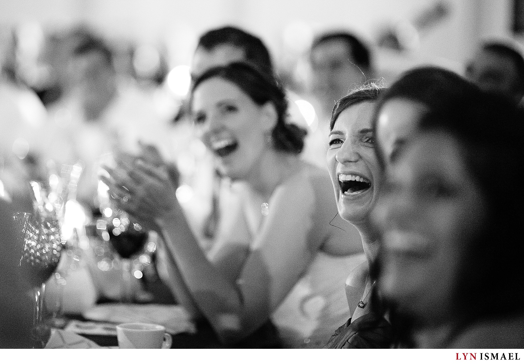The wedding party reacts to a hilarious video during a wedding reception.