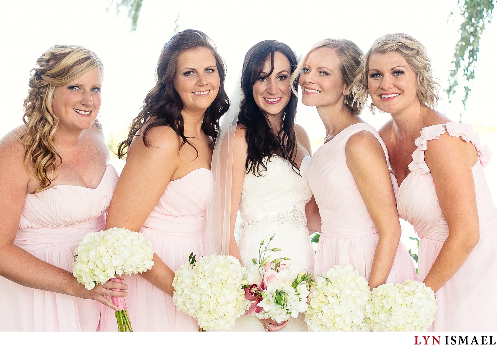 Bride and her bridesmaids wearing pink dresses.