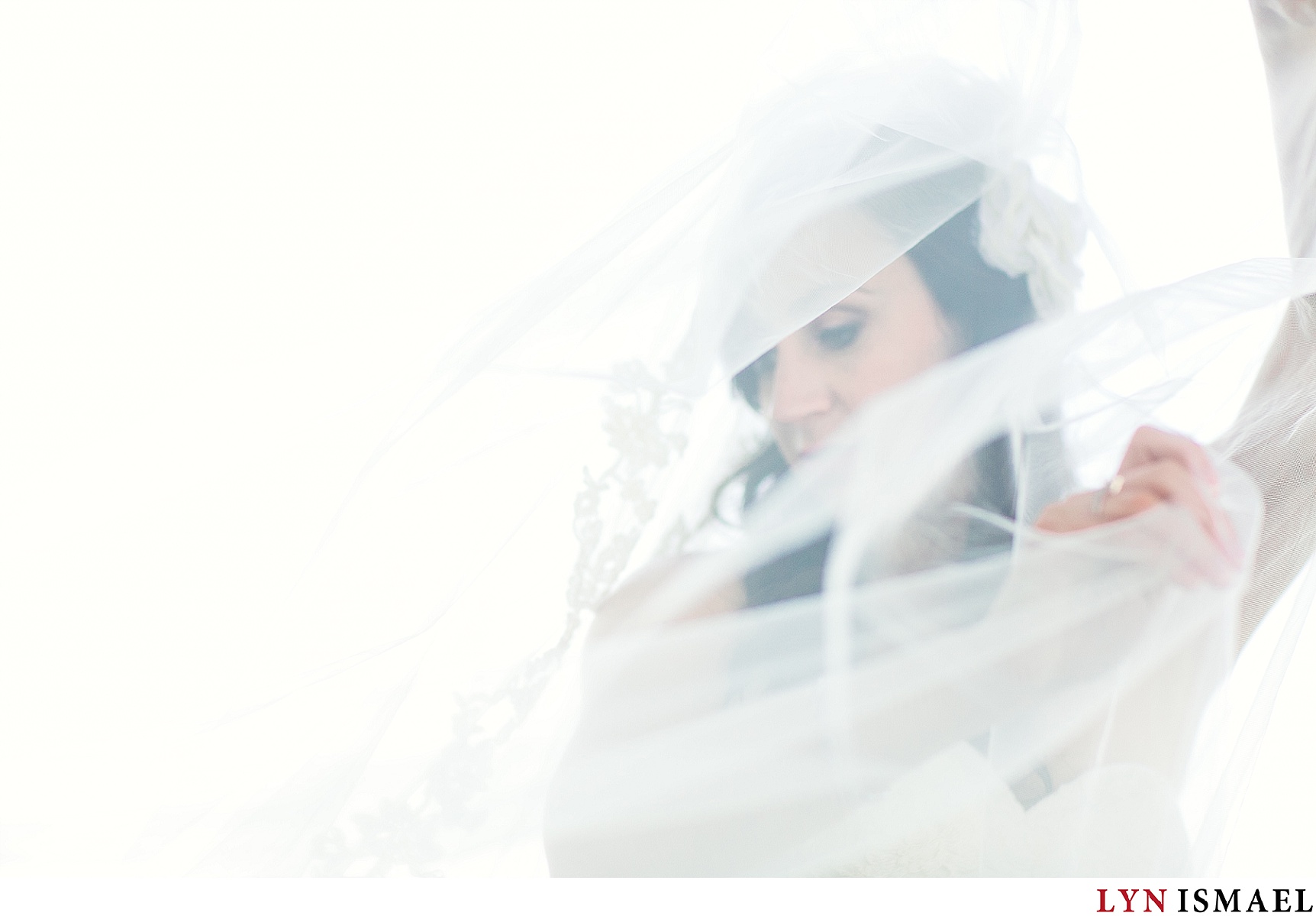 An artistic portrait of the bride using her veil.
