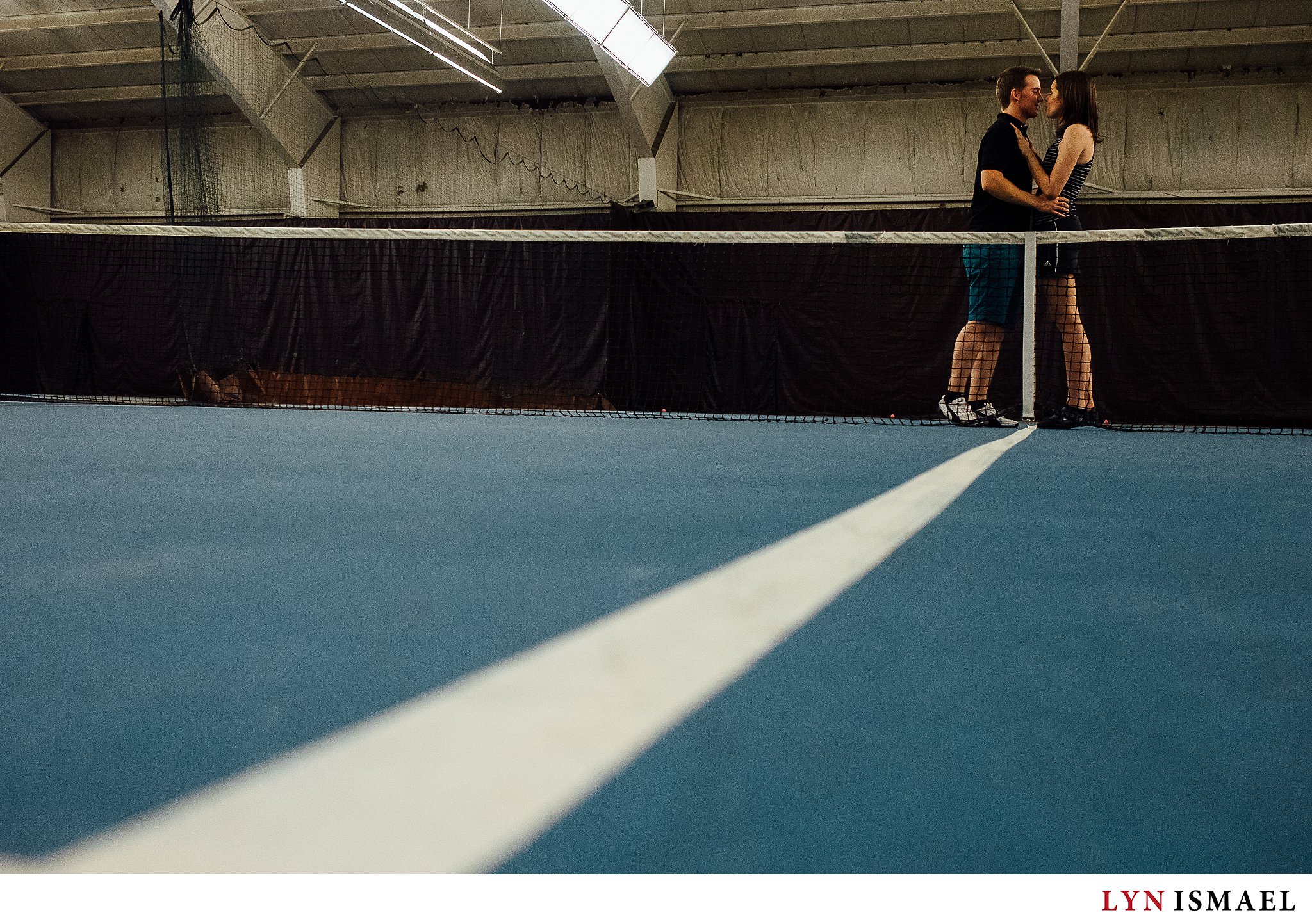 Engagement portrait at an indoor tennis court.