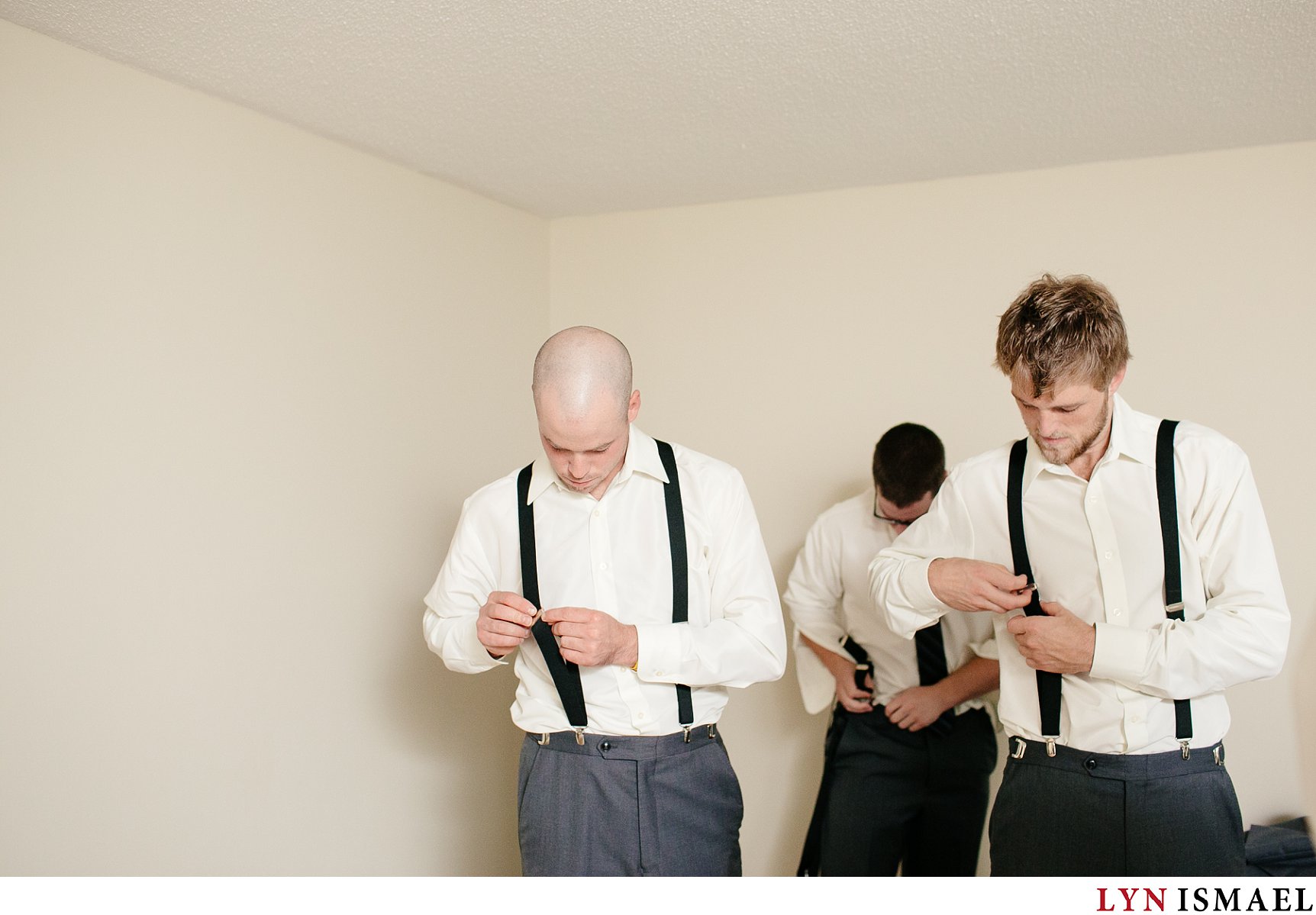 The groom and his groomsmen fix their suspenders.