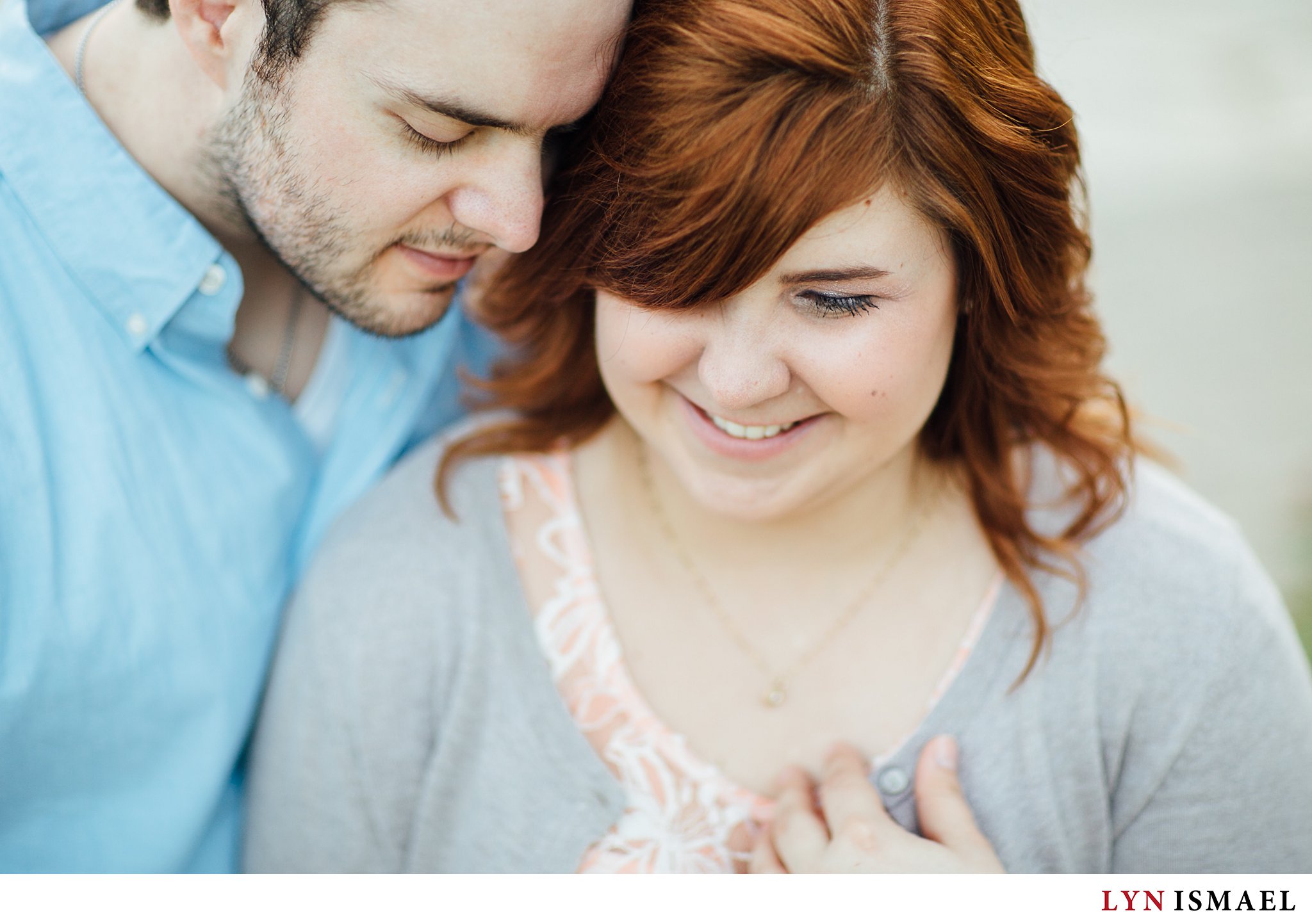 Beautiful red haired woman with her fiance poses for their engagement session.