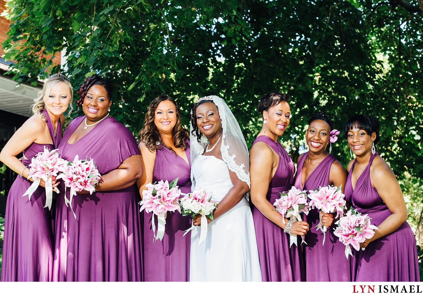 Bridesmaids wearing purple dresses and holding bouquets made of lilies