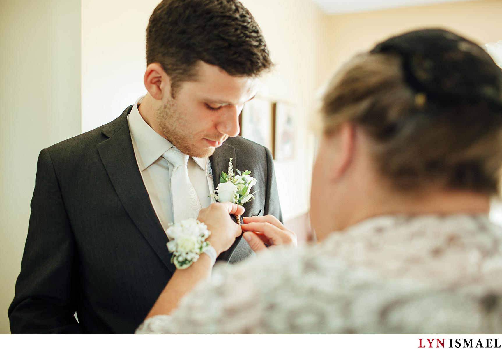 Mother of the groom pins his flowers.
