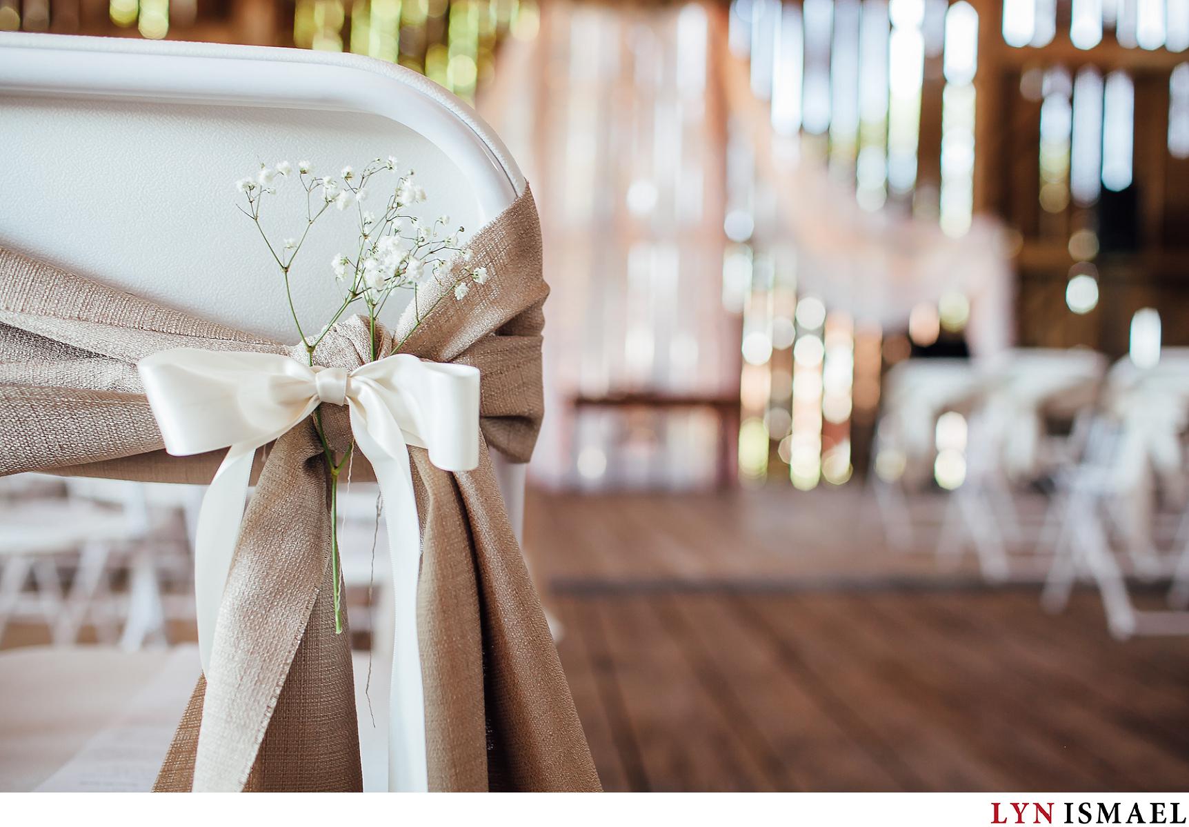 wedding chairs adorned with baby's breath and beige ribbon