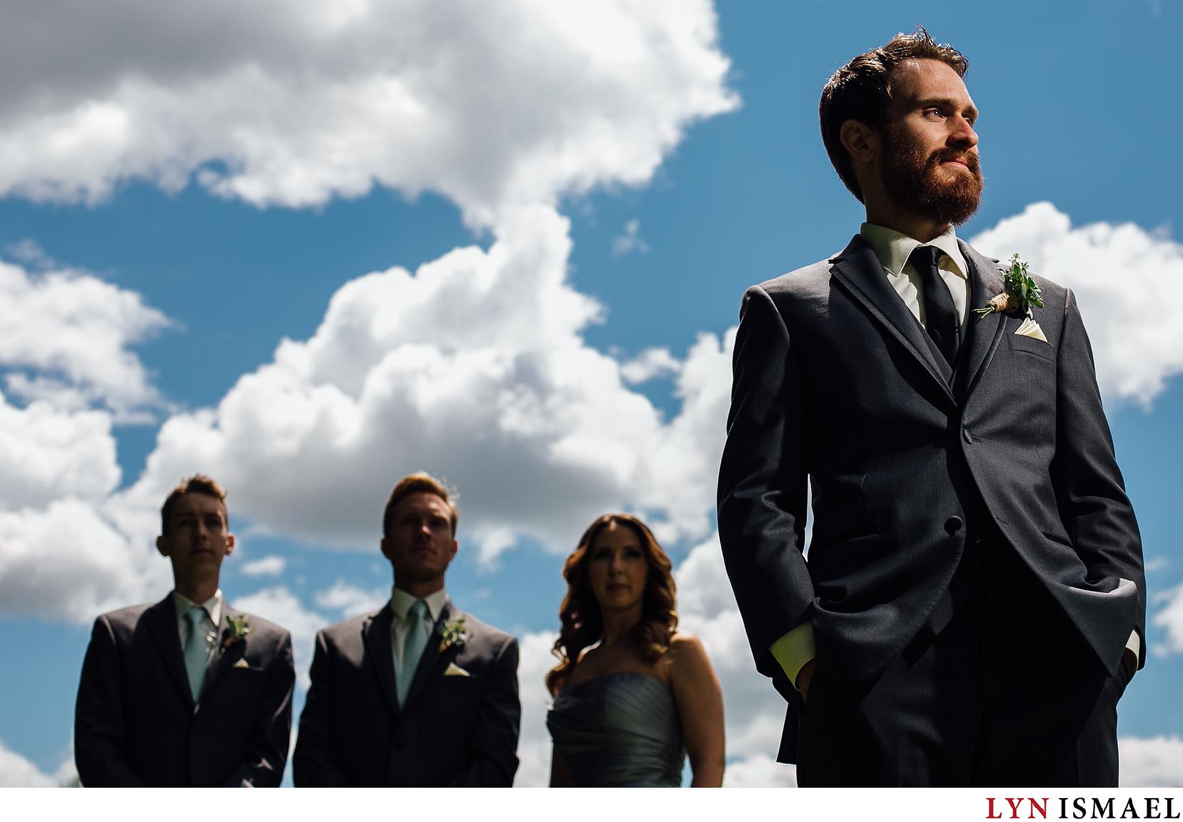 A dramatic portrait of the groom with his groomsmen and groom's woman photographed by a Waterloo Region wedding photographer.