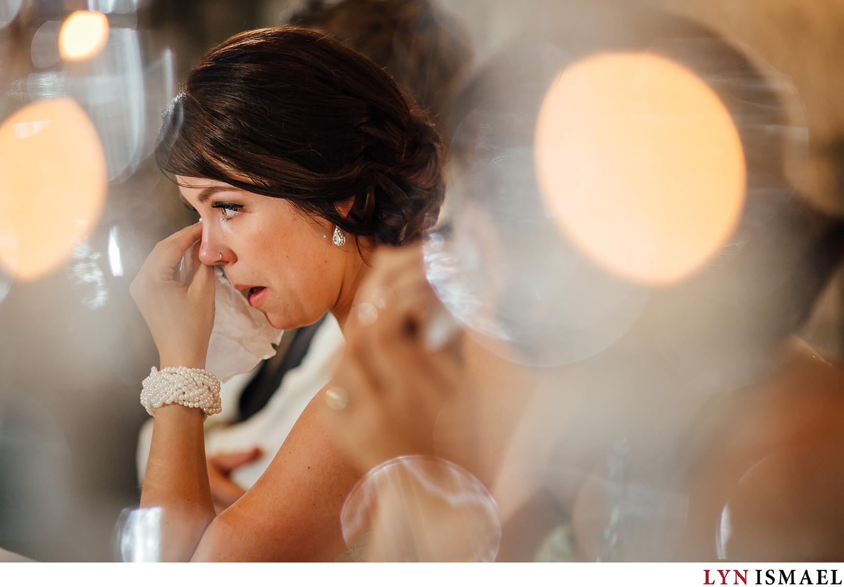 A bride is photographed wiping her tears by a Waterloo Region wedding photographer.