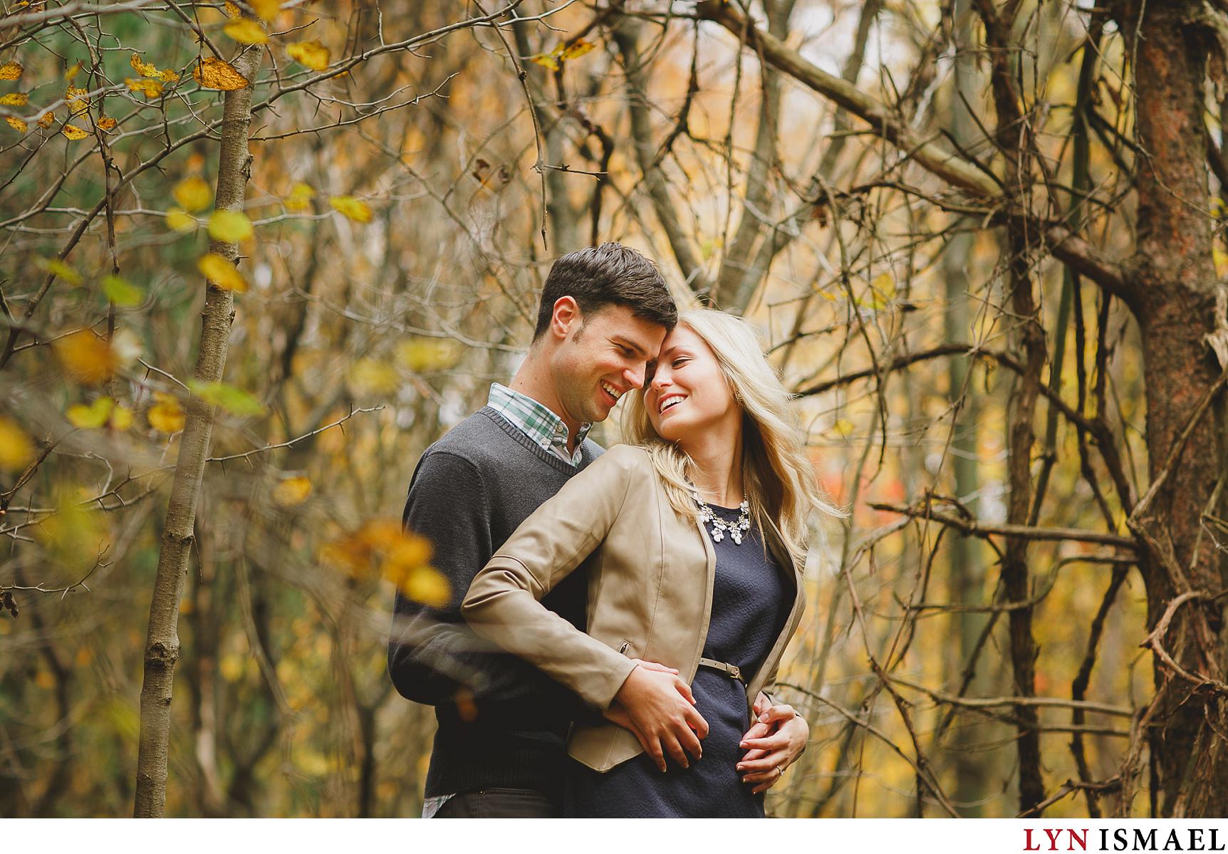 An engaged couple poses for their engagement photos they shot in the fall.