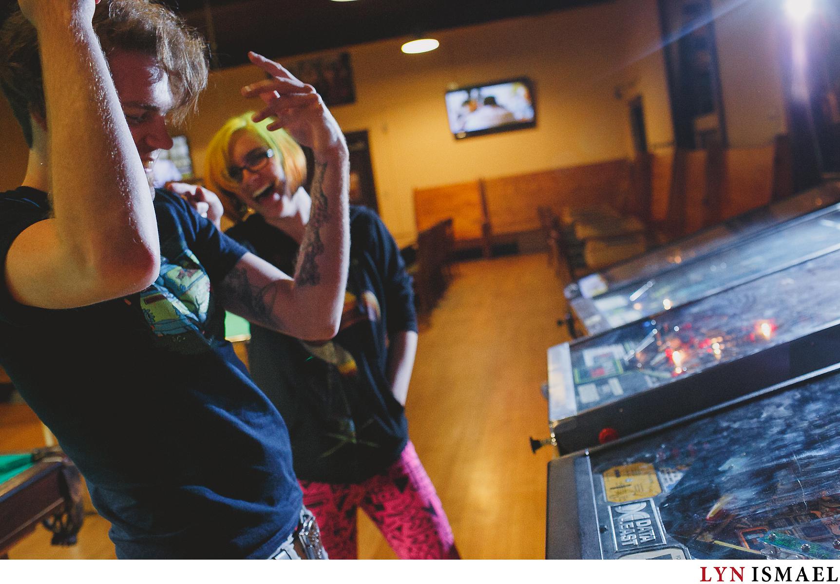 A couple plays with pinball machines for their engagement session in Waterloo, Ontario.