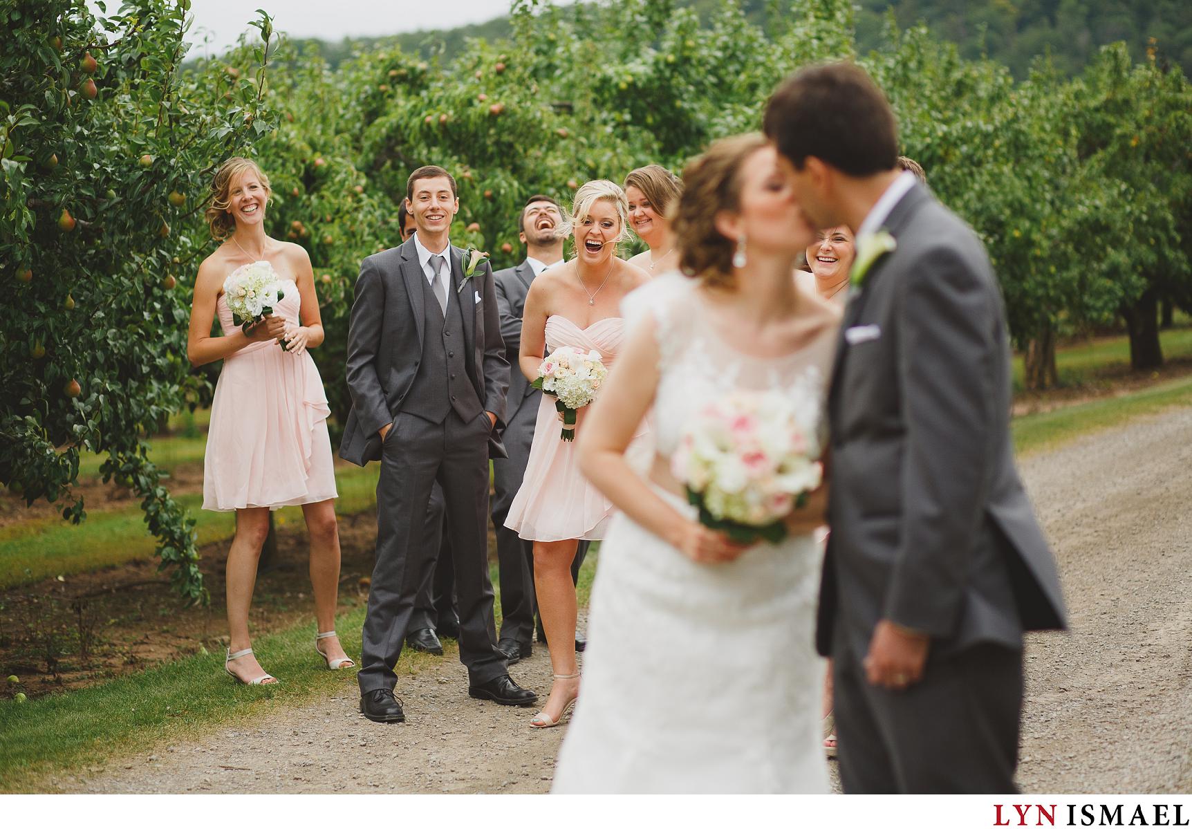 Wedding party reacts to the bride and groom kissing.