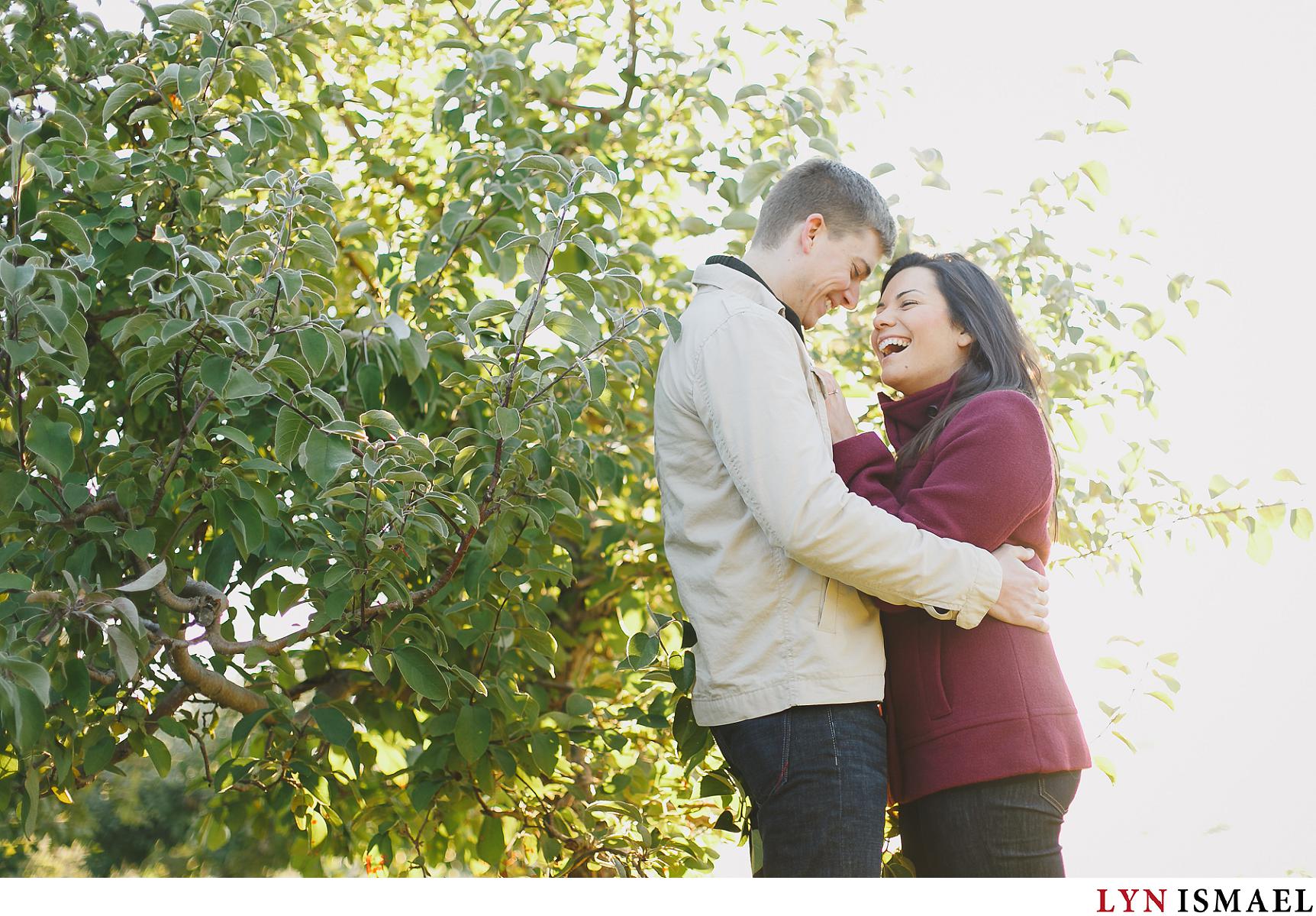 An engaged couple having a great time at their apple orchard fall engagement session