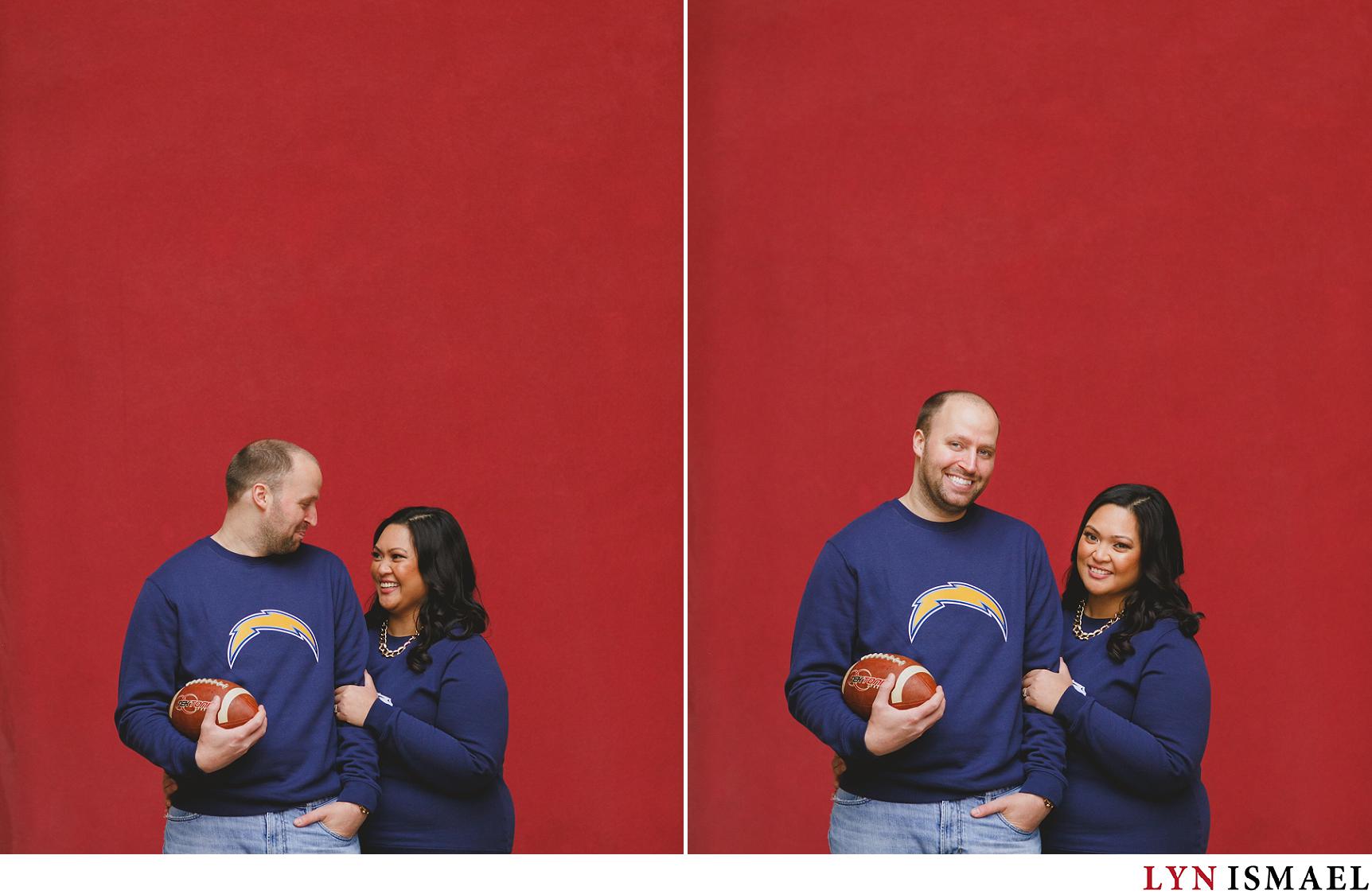 A couple in front of a red wall at Mississauga Civic Centre wearing their favourite sport sweatshirts