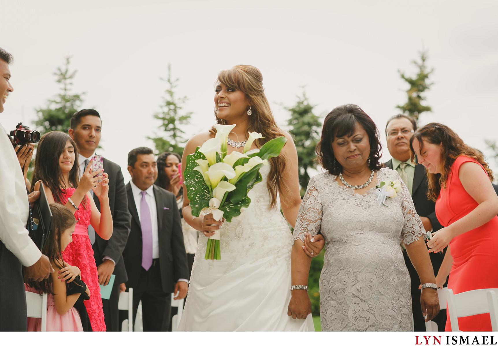 A mother walks down the aisle with her daughter to give her away on her wedding day.