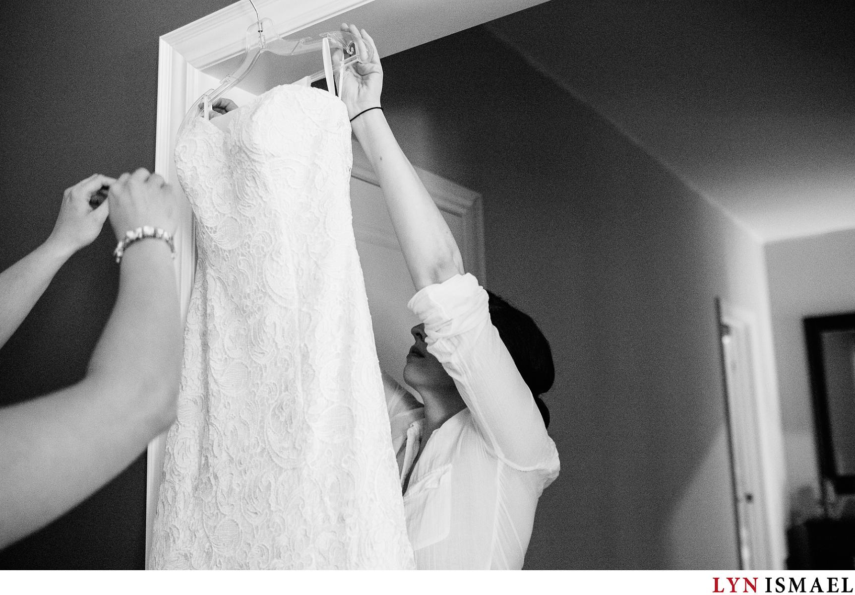 Bride reaches for her wedding gown hanging.