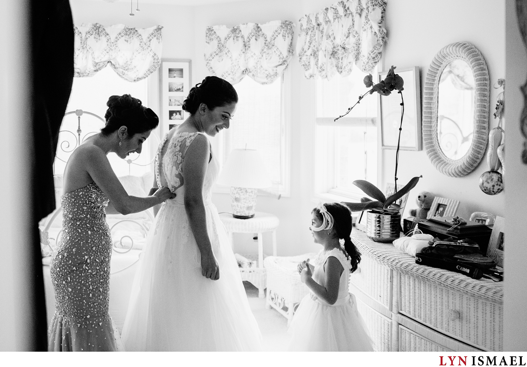 Flower girl looks admiringly at the bride as she got dressed in her wedding gown.