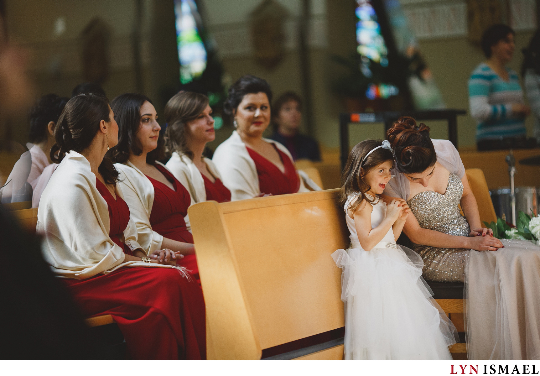 A flower girl talking to the maid of honour at a wedding ceremony at St David's Parish Church in Vaughan, Ontario.