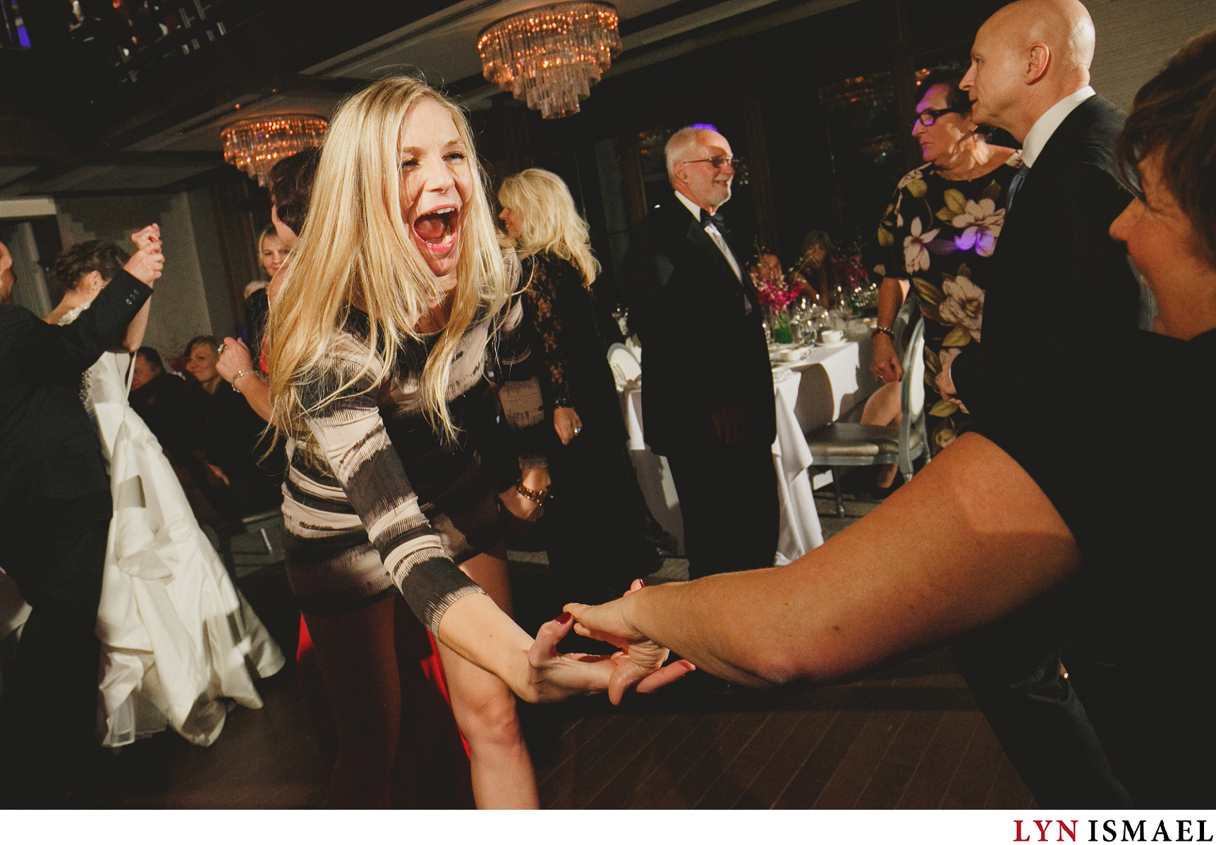 Moment driven wedding photographer captures guests at the Grandview Room of Whistle Bear Golf Club happily dancing.