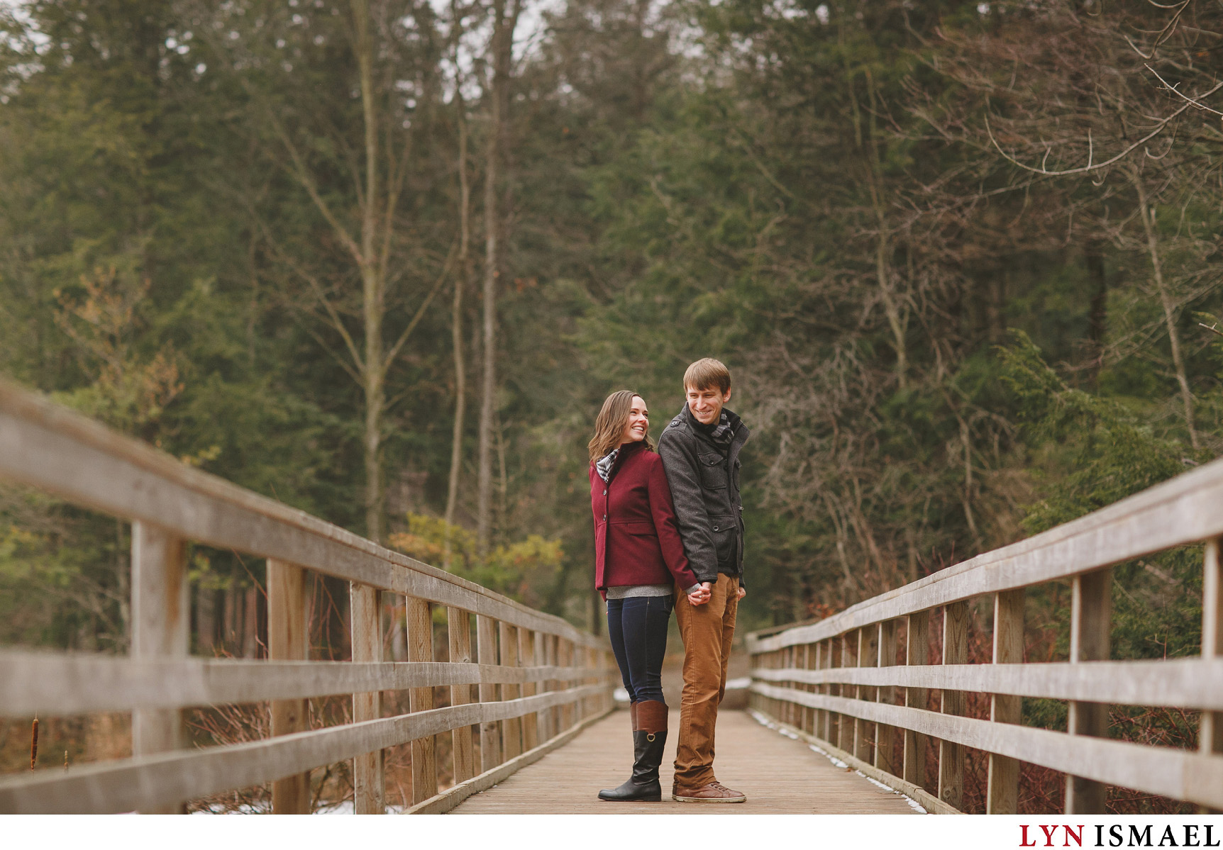 A happy couple poses for their winter woodland engagement session in Kitchener, Ontario.