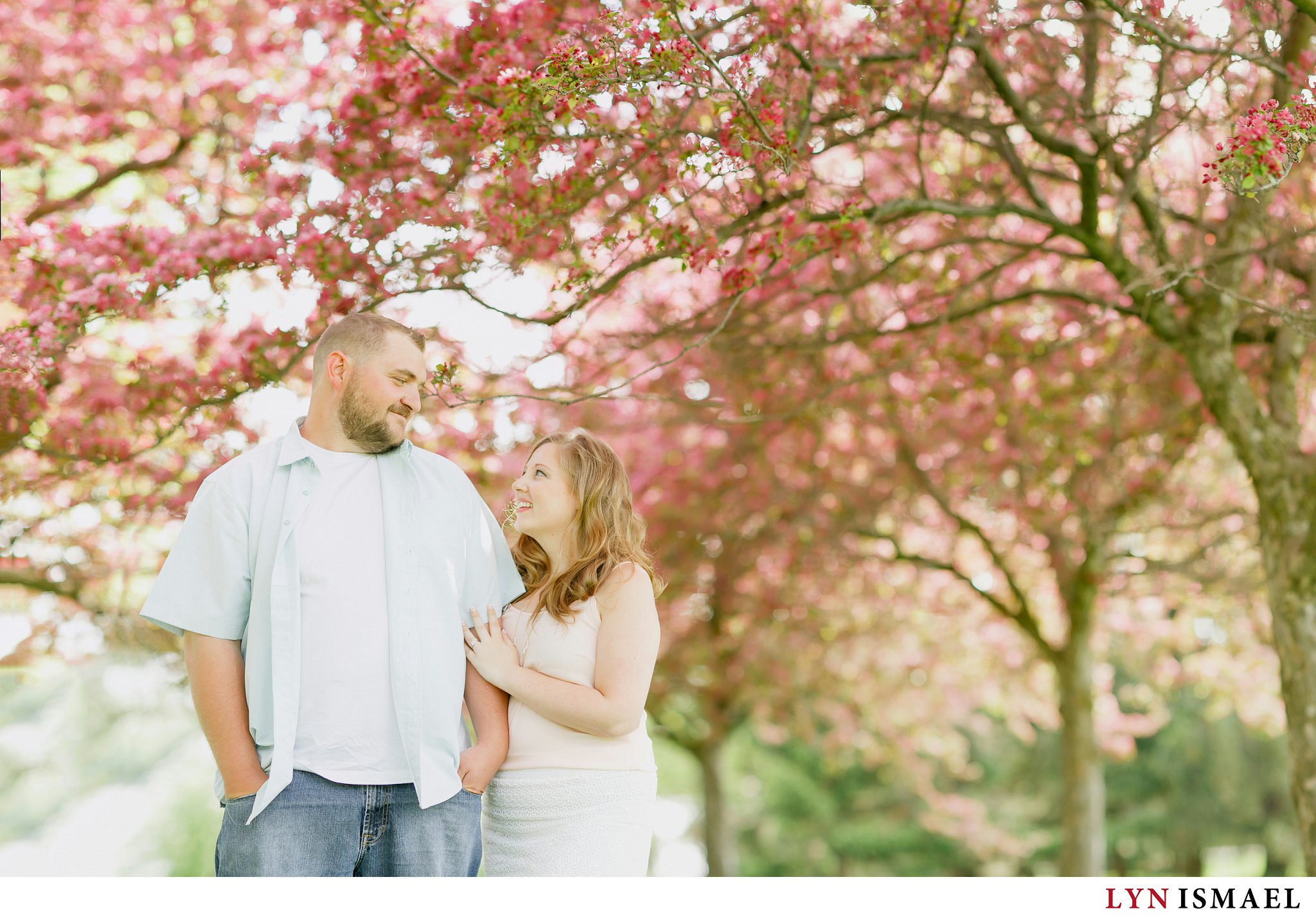 An engagement session under pink blossoms.