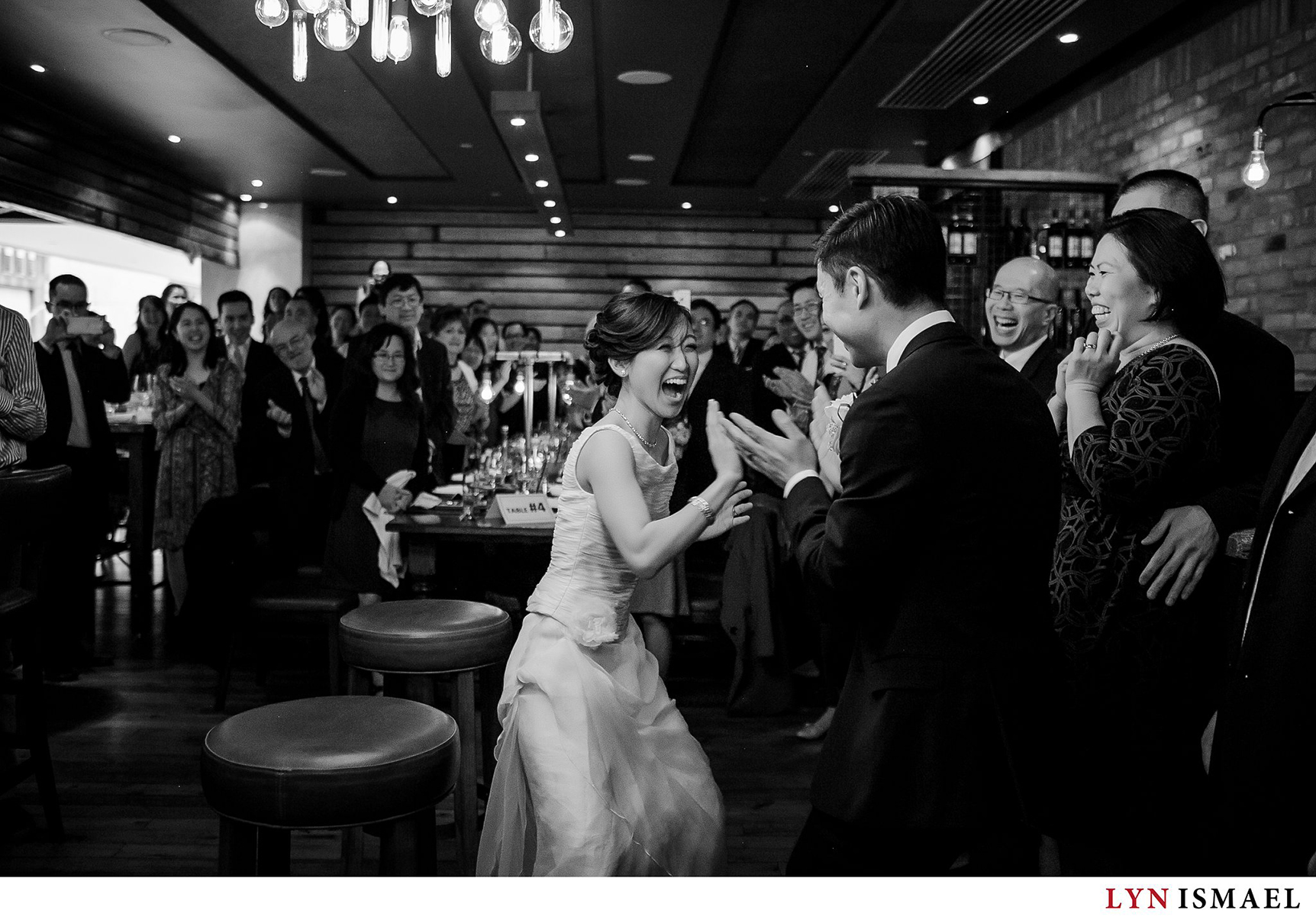 Moment driven wedding photographer captures the bride and groom's entrance at their wedding reception at Reds Wine Tavern in Toronto, Ontario.