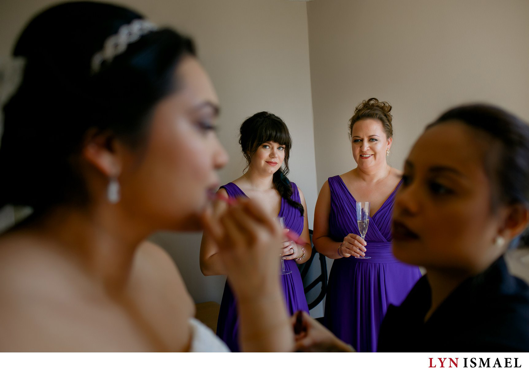 Bridesmaids watch the makeup artist touchup the bride's makeup.